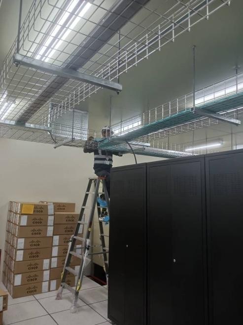 Technician working on cabling above server racks