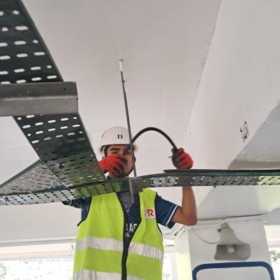 Technician installing in-building coverage cabling under a cable tray